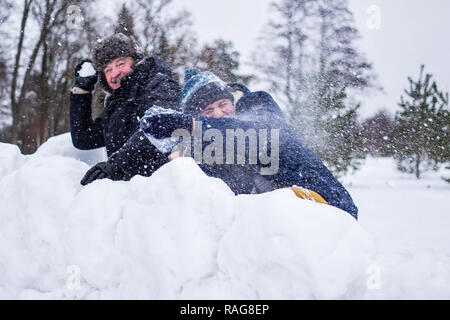 Un homme et son jeune fils de lancer une balle de neige, Banque D'Images