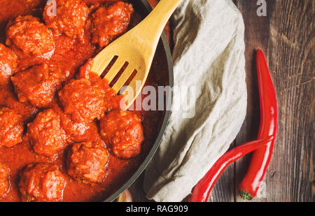 Boulettes de viande avec sauce tomate dans la poêle en fonte sur fond de bois rustique. Vue d'en haut. Banque D'Images