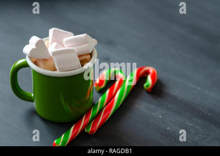 Chocolat chaud avec des guimauves dans une tasse en céramique et sucre de canne de Noël sur la table en bois. Banque D'Images