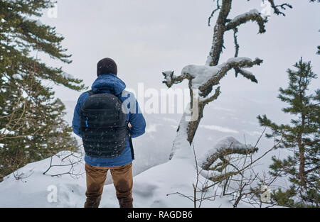 L'homme avec un sac à dos sur le dessus d'une montagne enneigée Banque D'Images