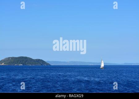 Petit bateau à voile à l'île avec en arrière-plan Banque D'Images