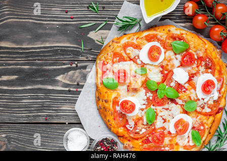 Des pizzas Margherita avec tomates, basilic, romarin et de mozzarella sur fond de bois rustique. Vue de dessus with copy space Banque D'Images