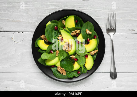 À l'avocat salade végétalienne, épinards, de grenade et de noix dans la plaque noire avec une fourchette. alimentation saine. Vue de dessus Banque D'Images