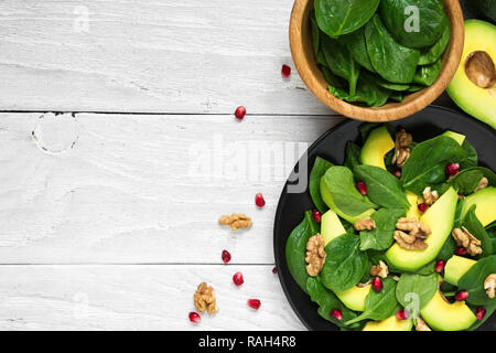 Salade végétarienne fraîche avec de l'avocat, épinards, grenade et noix en plaque noire. alimentation saine. top view with copy space Banque D'Images