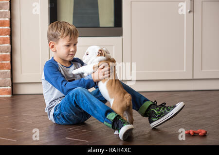 Cute boy playing with puppy bulldog Anglais sur cuisine. Banque D'Images