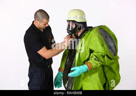 Aider un collègue pompier mis sur une combinaison de protection chimique avec de l'alimentation en air de l'appareil respiratoire à air comprimé, Banque D'Images