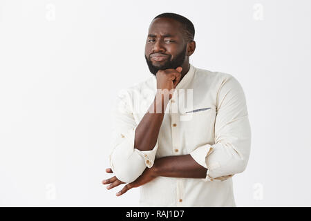 Nah, pas impressionnant, en doute. Pas mécontent de belles emotive African American man en chemise blanche, holding de poing sur le menton et les sourcils avec expression douteuse, hésitant ou incrédules Banque D'Images