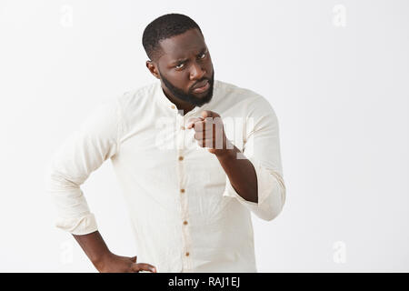 Gronder l'homme, petite amie pour lui dire de sa faute. Mécontents en colère African American male avec barbe en chemise blanche officielle, tenant la main sur la taille de l'appareil photo et en montrant avec index, leçon d'enseignement Banque D'Images