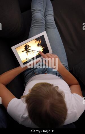 Jeune femme assise sur un canapé et le surf avec un iPad, tablet computer, accès internet sans fil Banque D'Images