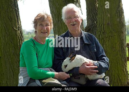 Vieux couple tenant un lapin dans une ferme pour enfants ou zoo, Wilhelmsburg, Hambourg Banque D'Images