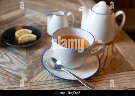 Thé Earl Grey servi avec des morceaux de citron. Le thé est servi dans une théière. Banque D'Images