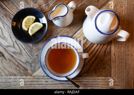 Thé Earl Grey servi avec des morceaux de citron. Le thé est servi dans une théière. Banque D'Images