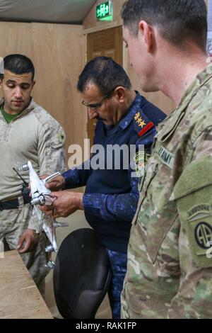 Un Irakien d'officier des opérations de la police fédérale (centre), de l'armée américaine le Capitaine Scott Sikora (à droite), un agent du personnel affecté au 1er Escadron, 73e Régiment de cavalerie, 2e Brigade Combat Team, 82e Division aéroportée, et U.S. Marine Cpl. Ali Mohammed (à gauche), un traducteur et un marin d'alimentation avec 3e Bataillon, 7e Régiment de Marines, marines à des fins spéciales Les Force-Crisis Response-Central Tâche Commande, inspecter un véhicule aérien sans pilote ISIL capturés au cours d'un échange de renseignement à l'engagement du chef du Centre d'opérations commun à Qayyarah Aérodrome de l'Ouest, de l'Iraq, le 9 février 2017. Déployées à l'appui de Banque D'Images