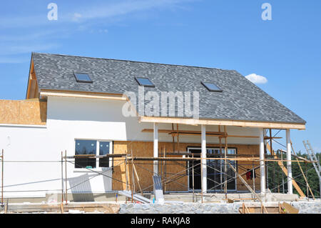 Grenier sous le toit. La construction de la toiture de l'extérieur. Construction d'une maison avec toit de bardeaux d'asphalte, lucarnes, terrasse patio, peinture des murs à l'extérieur. Banque D'Images