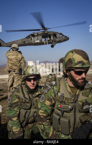 L'armée américaine et de soldats portugais, attribué à Bataille multinationales Group-East l'avant poste de commandement, conduite des opérations de charge avec un UH-60 Black Hawk piloté par des soldats de l'armée américaine, d'MNBG-Est Sud de poste de commandement, le Camp Bondsteel, au Kosovo, le 16 février. Au cours de la formation, les soldats ont attaché des blocs de béton au fond des hélicoptères en vol stationnaire pour simuler le chargement d'un véhicule de l'élingue pour de futures missions. Banque D'Images