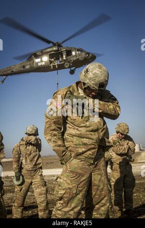 Les soldats de l'armée américaine, attribué à Bataille multinationales Group-East l'avant poste de commandement, conduite des opérations de charge avec un UH-60 Black Hawk piloté par des soldats de l'armée américaine, d'MNBG-Est Sud de poste de commandement, le Camp Bondsteel, au Kosovo, le 16 février. Les soldats de l'armée américaine a effectué l'entraînement aux côtés de leurs homologues de l'OTAN portugais dans le cadre de leur mission de fournir un environnement sûr et sécuritaire à l'intérieur du Kosovo. Banque D'Images