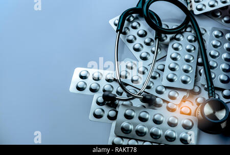 Tas de comprimés comprimés dans l'argent d'aluminium blister et stéthoscope sur fond blanc. L'industrie pharmaceutique. L'utilisation des médicaments à l'hôpital. Healt Banque D'Images