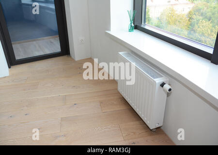 Chauffage avec thermostat de radiateur blanc pour l'économie d'énergie dans la maison inachevée réparation chambre avec balcon porte. Banque D'Images