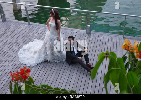 Un couple de jeunes mariés à Singapour se détendre lors d'une séance de photos de mariage, et pour l'événement Plaza, Marina Bay, un endroit populaire pour la photographie de mariage Banque D'Images