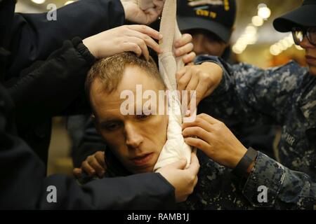 NEWPORT NEWS, Virginie (fév. 13, 2017) -- Hôpital Corpsman 2e classe Ryan Shortridge, affecté à l'unité Pre-Commissioning Gerald R. Ford (CVN 78), est traité pour une simulation d'une lacération du visage pendant un brancardier d'entraînement à l'intérieur du hangar du navire. L'exercice a porté sur les premiers secours et d'intervention de l'état de préparation en vue de la livraison de Ford à la flotte. Banque D'Images