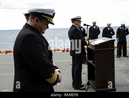 Océan Atlantique (fév. 18, 2016) - Le Capitaine James Midkiff, commandant du navire d'assaut amphibie USS Iwo Jima (DG 7), s'incline sa tête dans la prière lors d'une inhumation en mer la cérémonie. Les marins à bord de Iwo Jima a engagé un total de 18 militaires et deux membres de la famille à la mer. Banque D'Images