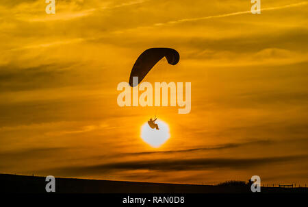 Firle, Lewes, East Sussex, Royaume-Uni. 4 janvier 2019. Parapente dans la brise Du Nord pendant que le soleil descend au-dessus des South Downs. Banque D'Images