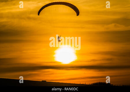 Firle, Lewes, East Sussex, Royaume-Uni. 4 janvier 2019. Parapente dans la brise Du Nord pendant que le soleil descend au-dessus des South Downs. Banque D'Images