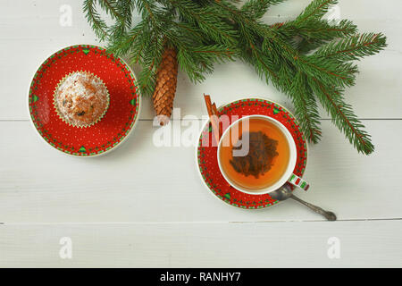 Fond de Noël avec des branches de sapins, des cônes, des décorations de Noël et tasse de thé chaud de fruits rouges avec deux pains. Close-up, vue du dessus sur vi Banque D'Images