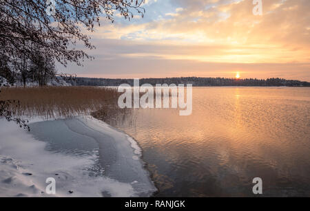 Superbe paysage d'hiver avec le coucher du soleil à icy et paisible lac de Finlande Banque D'Images