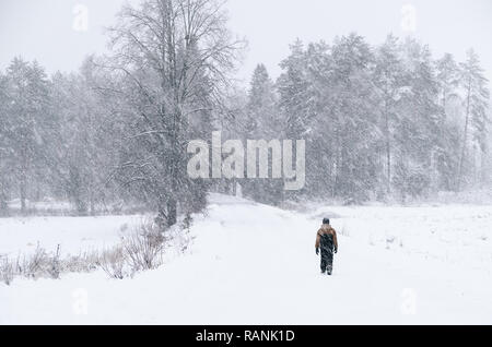 Lonely Boy walking road à paysage d'hiver avec neige lourde en Finlande Banque D'Images