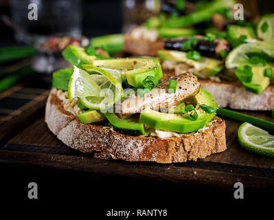 Sandwich - smorrebrod avec anchois, d'avocat et de fromage à la crème sur planche de bois. La cuisine danoise. Banque D'Images