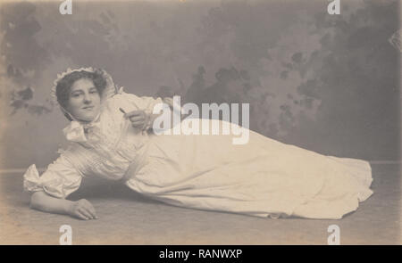 Vintage 1909 Studio Carte postale photographique d'une dame portant et semble être la tenue d'un mannequin d'enfant. Banque D'Images