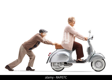 Full Length shot of a senior man pushing a senior woman riding a scooter vintage isolé sur fond blanc Banque D'Images