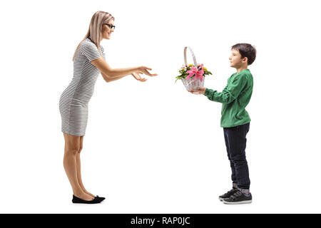 Tourné sur toute la longueur d'un jeune garçon donnant des fleurs à sa mère isolé sur fond blanc Banque D'Images