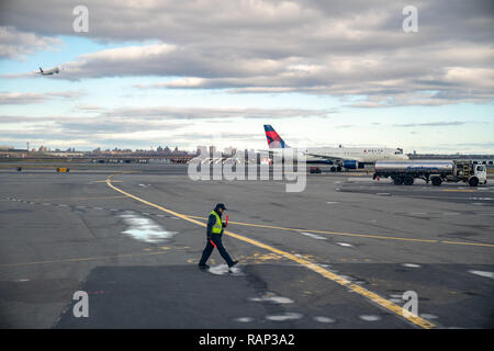 New York, USA, 29DEC 2018 - Une rampe promenades marshall sur le tarmac de New York La Guardia Airport comme il guide un avion s'est écarté de la porte. Banque D'Images