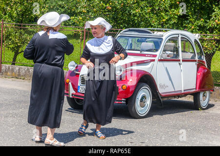 Deux femmes en costumes de nonne, une voiture de vétéran Citroën 2CV, version spéciale Charleston bicolore (combinaison de Bordeaux Delage Rouge et Blanc-gris) Banque D'Images