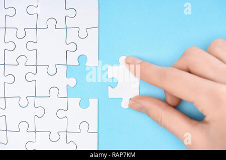 Vue partielle de la femme avec des morceaux de puzzles blanc sur fond bleu Banque D'Images