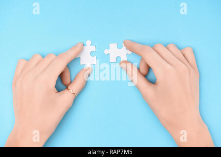 Vue partielle de woman holding pièces puzzles blanc sur fond bleu Banque D'Images