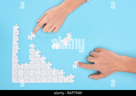 Cropped shot de l'homme et de la femme avec des pièces de puzzle blanc sur fond bleu, concept de coopération Banque D'Images