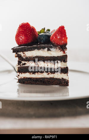 Morceau de gâteau délicieux whoopie pie avec les baies fraîches on white plate Banque D'Images