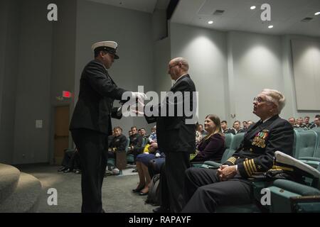 KEYPORT, Washington (fév. 27, 2017) Le chef de l'embarcation, chef technicien Sonar Neal Bederson, affecté à la Los Angeles-classe sous-marin d'attaque rapide USS Albuquerque (SSN 706), présente le Capitaine Richard Hartman (ret.), Albuquerque's premier commandant, avec l'enseigne du bateau pendant le déclassement cérémonie tenue à Keyport musée sous-marin. Commandé le 21 mai 1983, Albuquerque a déployé 21 fois, a participé à 18 grands exercices navals, et effectué 1075 plongées avec succès tout au long de l' bateaux de 33 années de service. Banque D'Images