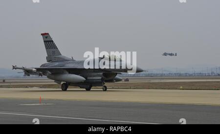 Un F-16 Fighting Falcon affecté à la 36e Escadron de chasse des taxis à la piste pour une mission de formation tout en un A-10 Thunderbolt II à partir de la 25e Escadron de chasse prend son envol au cours de l'effort du troupeau à Beverly 17-1 Osan Air Base, République de Corée, le 1 mars 2017. Les pilotes des deux escadrons de chasse a effectué plusieurs sorties durant l'exercice Beverly troupeau, perfectionner leurs compétences de vol et la capacité de travailler autour du paysage accidenté de Corée. Banque D'Images