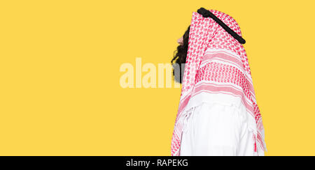 L'homme d'affaires arabe aux cheveux longs portant keffieh foulard traditionnel à côté de beauté, posent avec profil visage naturel avec sourire confiant. Banque D'Images