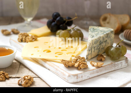 Apéritifs de différents types de fromage, raisins, noix et miel, servi avec des vins blanc et rouge. Style rustique. Banque D'Images