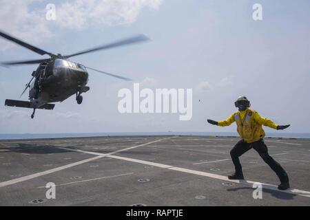 Golfe de Thaïlande (fév. 22, 2017) l'aviation de la Marine américaine maître de Manœuvre (manutention) Airman Amado Banos Derrickson signale à un hélicoptère Blackhawk UH-60Q, affecté à la 25e Brigade d'aviation de combat, qu'il décolle de l'transport amphibie USS dock Green Bay (LPD 20) au cours de l'effort d'Or 2017 Cobra. L'exercice est le plus grand théâtre de la coopération en matière de sécurité de l'exercice dans la région du Pacifique-Indo-Asia et fait partie intégrante de l'engagement des États-Unis pour renforcer l'engagement dans la région. Banque D'Images