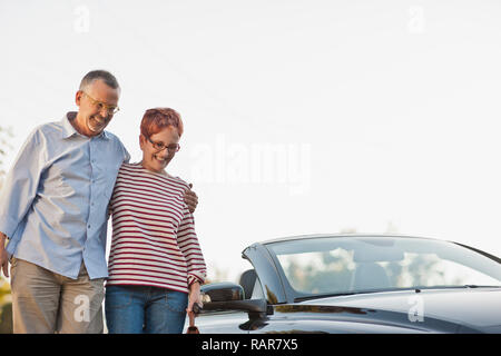 Smiling middle aged couple debout devant leur nouvelle voiture. Banque D'Images