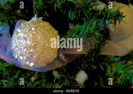 Vinyle blanc ornement sur un arbre de Noël entouré de feuillage ; close up de décoration d'arbre de Noël. Banque D'Images