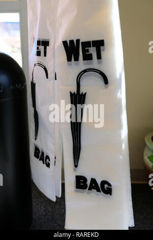 Sacs parapluie mouillé ; sacs en plastique pour les parapluies dans un immeuble de bureaux hall. Banque D'Images