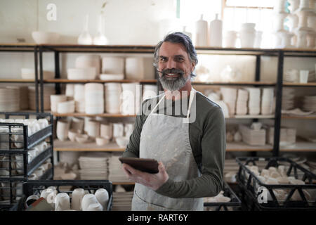 Potter souriant à l'aide de tablet entouré de travailler