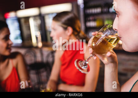 Femme buvant du vin blanc au night club Banque D'Images